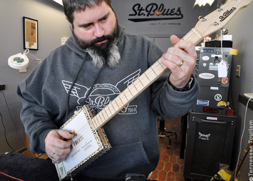 Gitarrenbauer Greg Mitchell demonstriert eine von ihm gebaute Cigar Box Guitar